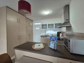 A kitchen with a microwave, a coffee maker, and a book on the counter.