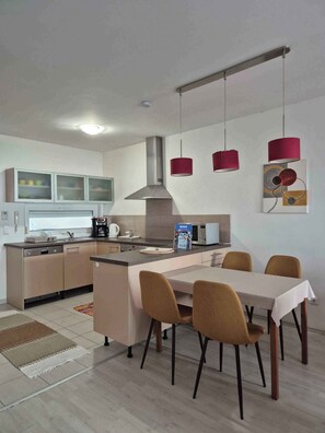 A modern kitchen with a central island, a dining area with chairs, and pendant lights.