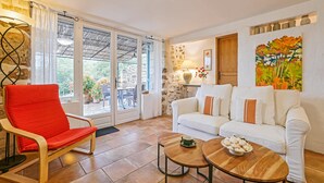 Una sala de estar con una silla roja, un sofá blanco y una mesa de centro de madera.