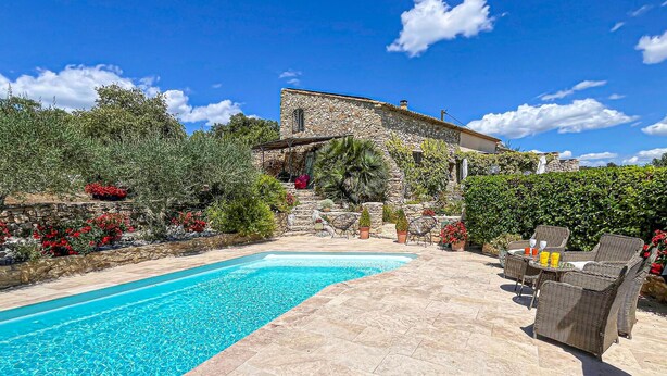 Un edificio de piedra con piscina y zona de estar al aire libre.