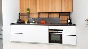 Una cocina moderna con armarios blancos, encimera negra y horno empotrado.