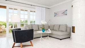 Una sala de estar moderna con una silla negra, un sofá gris y una pequeña mesa blanca con un florero.
