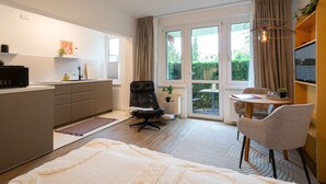 A modern kitchen with a dining area, a large window, and a view of greenery outside. - Dune garden Whg. Wa45-31 - Wa45-31 (Kühlungsborn)