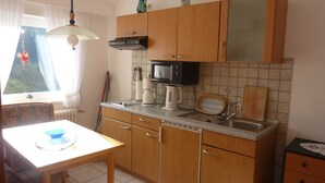 A compact kitchen with wooden cabinets, a microwave, a coffee maker, and a sink.