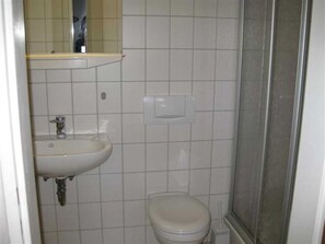 Une petite salle de bain avec un lavabo, des toilettes et un miroir au-dessus du lavabo.