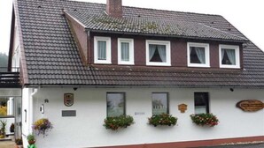 A white building with a tiled roof, multiple windows, and flower boxes on the facade.