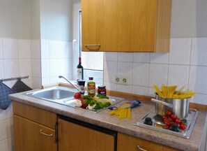 Una cucina con lavello, piano di lavoro e pensili in legno.