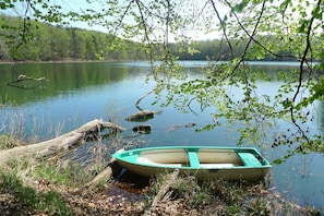 Ein kleines Boot, an einem Baumstamm an einem ruhigen See vertäut, umgeben von Bäumen.