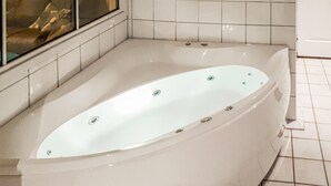 Een moderne badkamer met een vrijstaand bad, betegelde wanden en een raam met uitzicht.