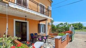 A two-story building with a balcony, outdoor seating area, and a garden with red flowers. - 2 bedroom amazing apartment in Pula (Pula)