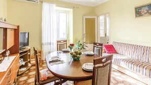 A dining area with a round table, chairs, and a television. There is a sofa with a patterned cushion and a painting on the wall. - 2 bedroom amazing apartment in Pula (Pula)