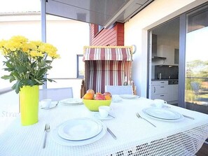 A dining table set with plates, cutlery, a bowl of fruit, and a yellow vase with flowers.