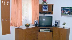 A corner room with a wooden cabinet, television, and speakers.