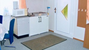 A compact kitchen with white cabinets, a microwave, a sink, and a door with a geometric design.