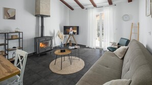 A living room with a fireplace, a television, a sofa, and a wooden table. - Amazing home in Kranjci (Kranjci)
