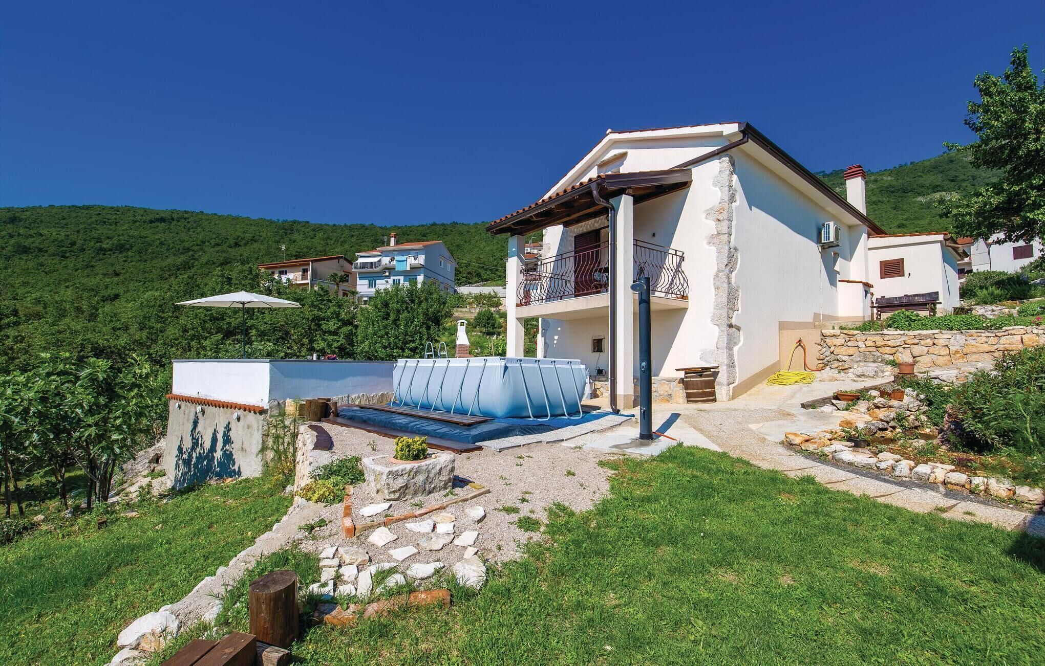 Ein Haus mit Swimmingpool, einer Steinmauer und Blick auf die umliegende Grünfläche.