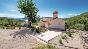 A rustic house with a red-tiled roof, surrounded by a gravel driveway and a large tree. - Nice home in Moscenicka Draga with WiFi (Moscenicka Draga)