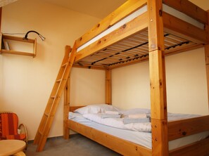 A bunk bed with a wooden frame and a shelf above it.