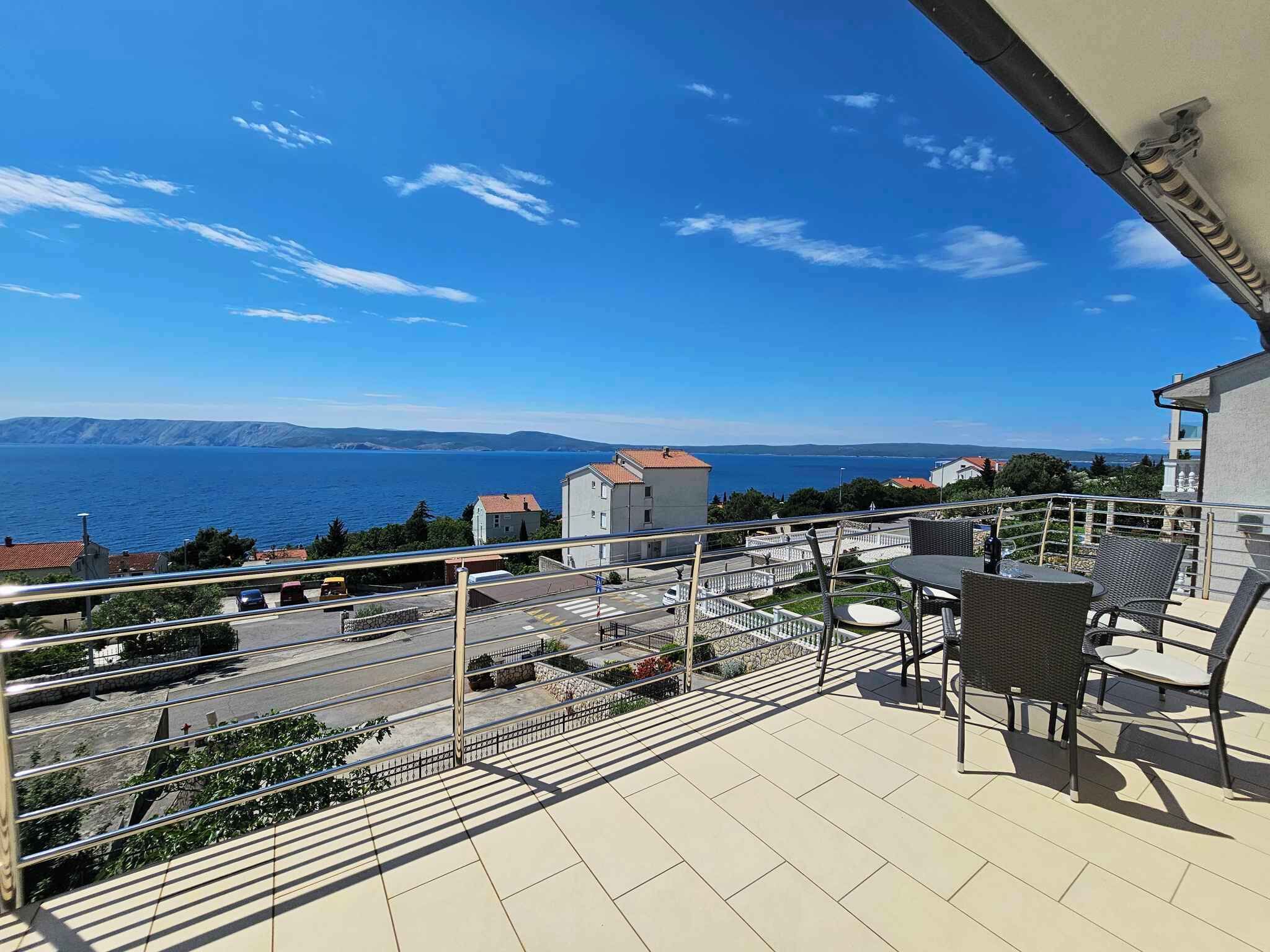 Een balkon met buitenmeubilair en uitzicht op de kust.