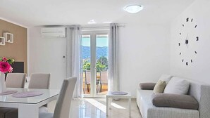 Un soggiorno moderno con zona pranzo, divano e vista sull'esterno.