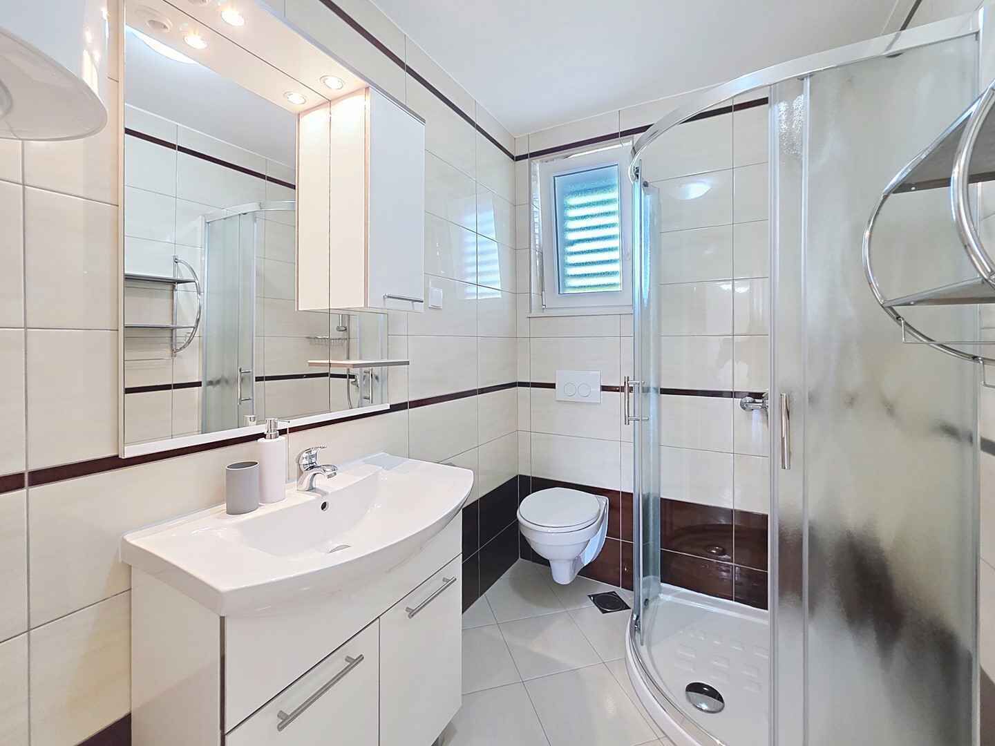 Une salle de bain moderne avec une douche à parois de verre, un lavabo blanc et des toilettes.