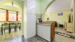 A compact kitchen with a microwave, a small sink, and a dining area with a table and chairs. - 2 bedroom cozy apartment in Pula (Pula)