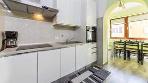A modern kitchen with white cabinets, a stainless steel range hood, a built-in oven, and a coffee maker. - 2 bedroom cozy apartment in Pula (Pula)
