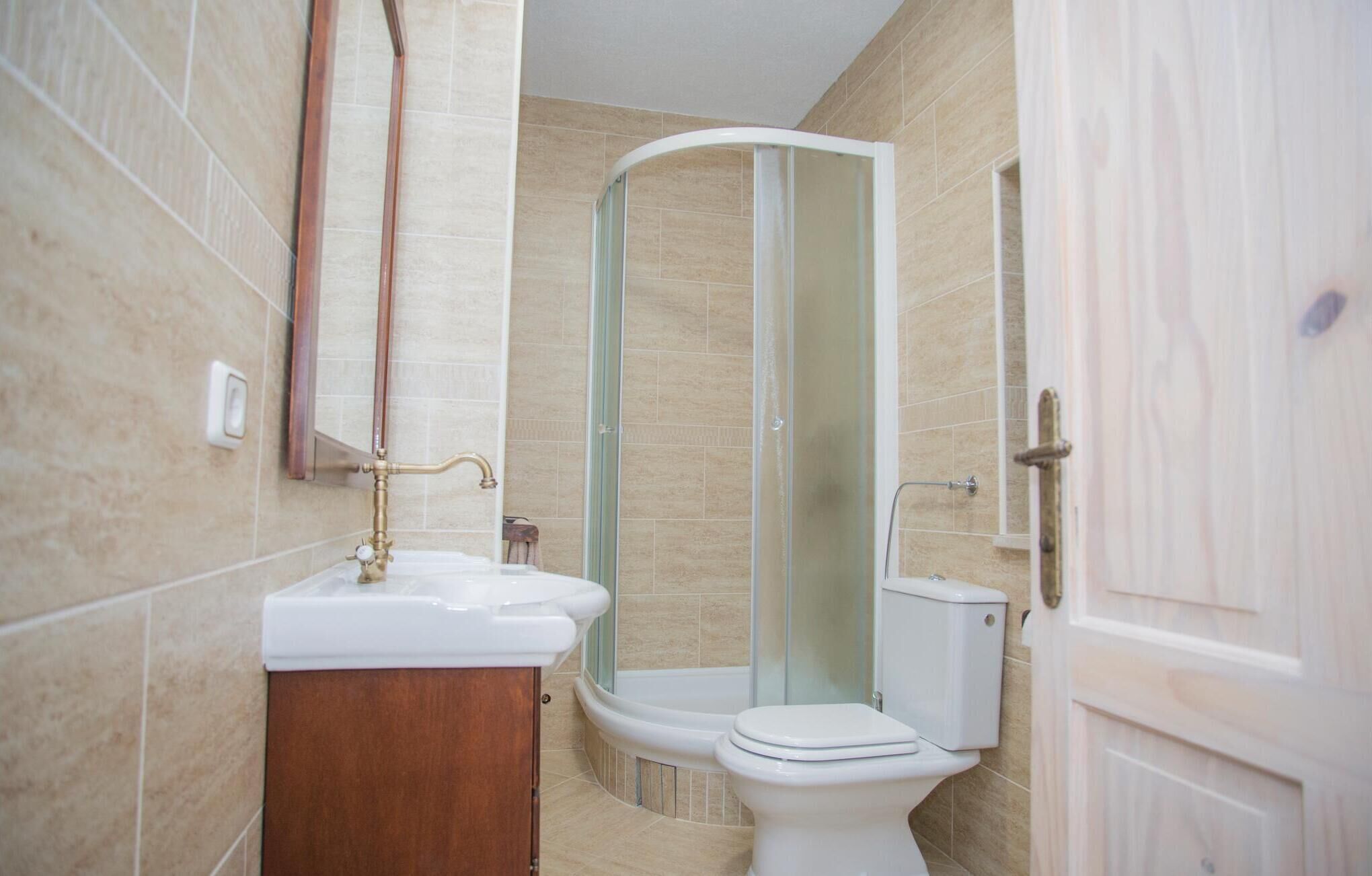 A bathroom with a white sink, a toilet, and a glass-enclosed shower.