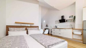 Una habitación de hotel moderna con una cama grande, un escritorio y una kitchenette.
