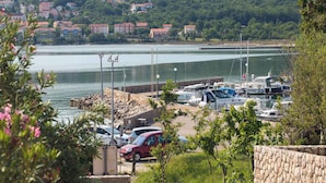 A marina with boats, a parking area, and a hillside with buildings in the background. - Holiday apartment 50 m from the beach (Čižići)