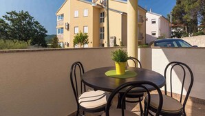 A balcony with a round table and chairs, a potted plant, and a building in the background. - Holiday apartment 50 m from the beach (Čižići)