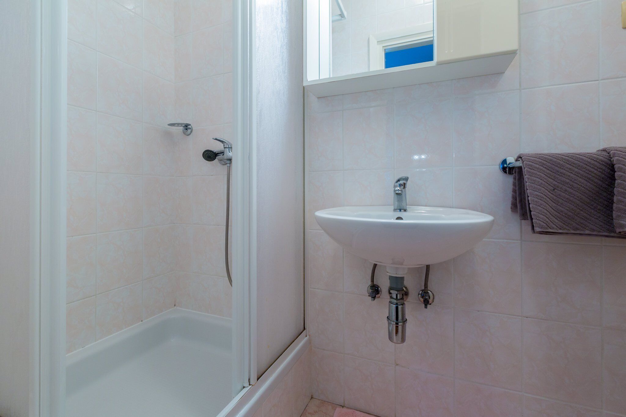 A bathroom with a shower, a sink, and a towel rack.