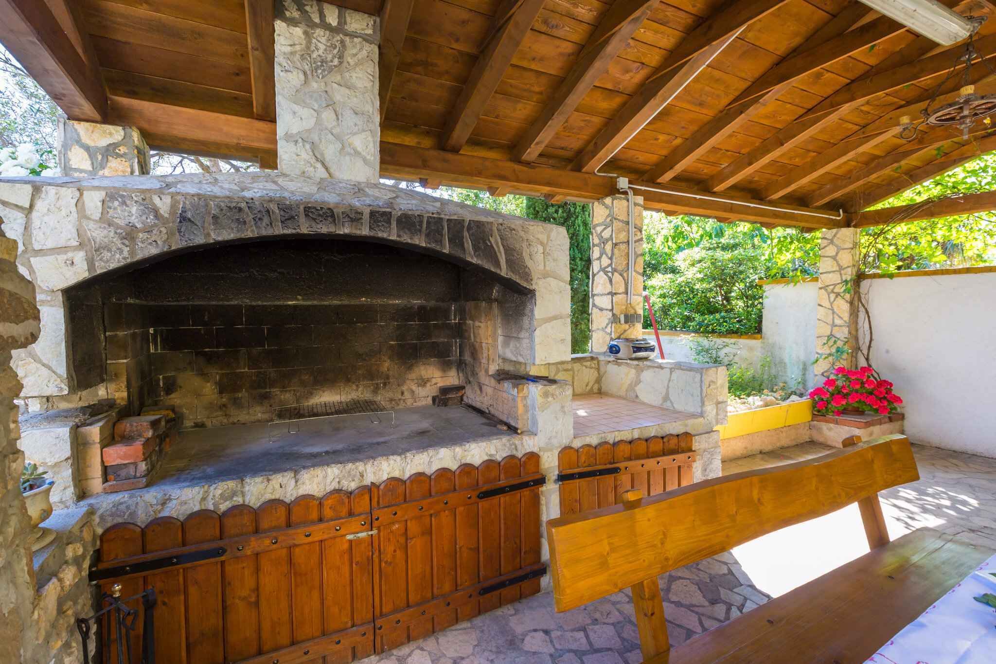 Una chimenea de piedra al aire libre con un banco de madera y una valla de madera.