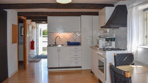 Een kleine keuken met witte kastjes, een gasfornuis en een koffiezetapparaat.