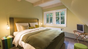 Une chambre à coucher avec un lit, une lampe de chevet, une fenêtre et un téléviseur posé sur une petite table.