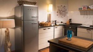 Une cuisine moderne dotée d’un réfrigérateur en acier inoxydable, d’un plan de travail en bois et d’un espace de rangement pour les bouteilles de vin.