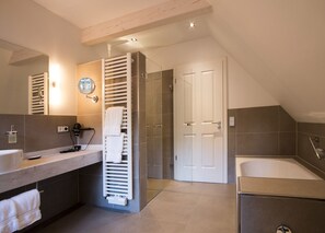 Un baño moderno con un espejo grande, toallero, zona de ducha y bañera.