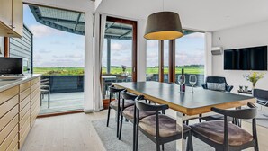 A modern kitchen with a large island, a dining area with a view, and a TV mounted on the wall. - Amazing home in Rømø with sauna (Rømø)