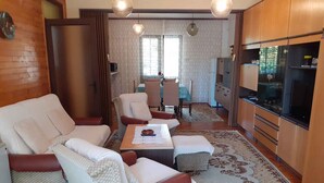 Una sala de estar con sofá, sillones, una mesa de centro y televisor.