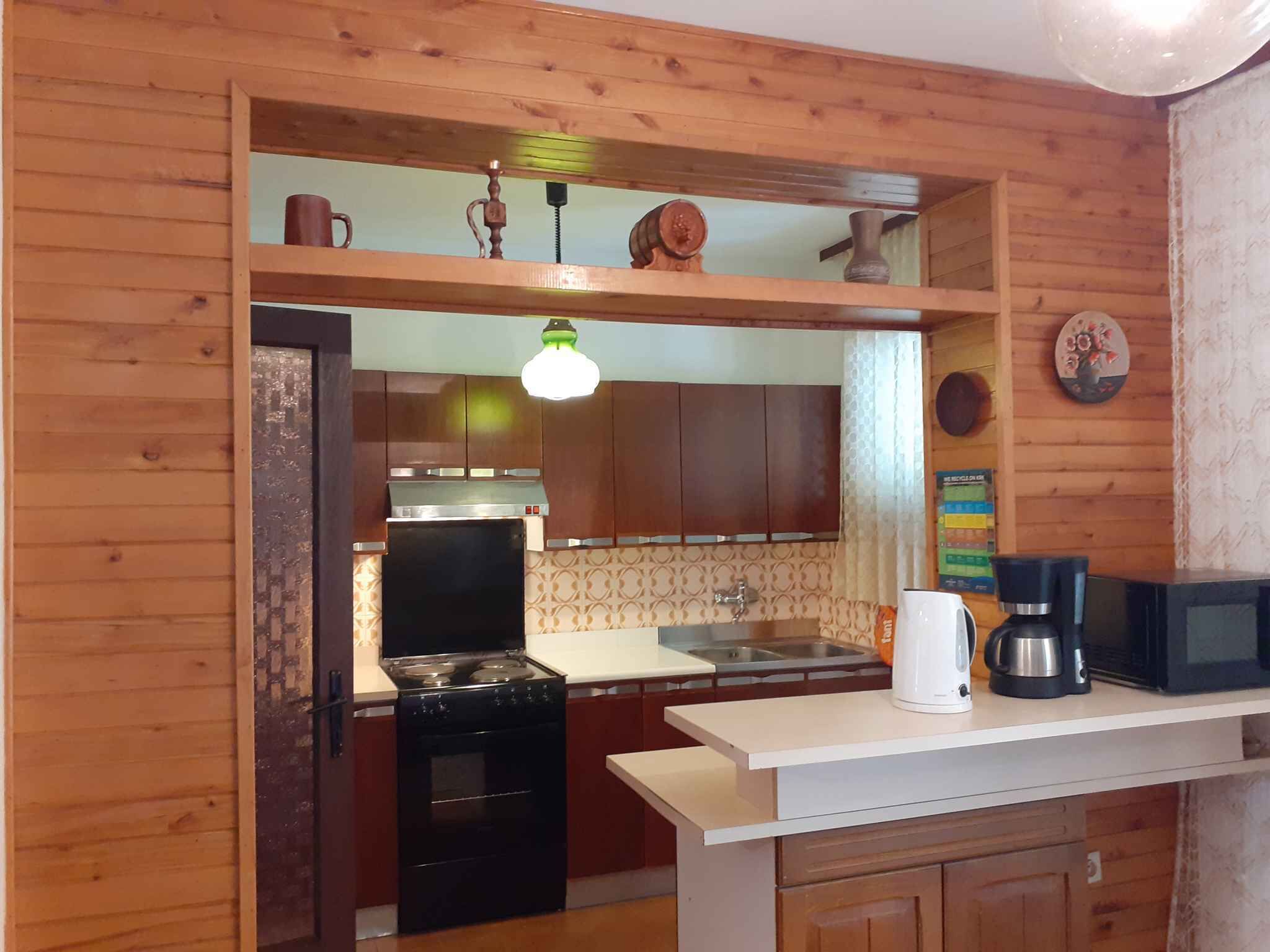 Una cocina con armarios de madera, estufa, lavamanos y microondas.