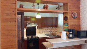 Una cocina con armarios de madera, estufa, lavamanos y microondas.
