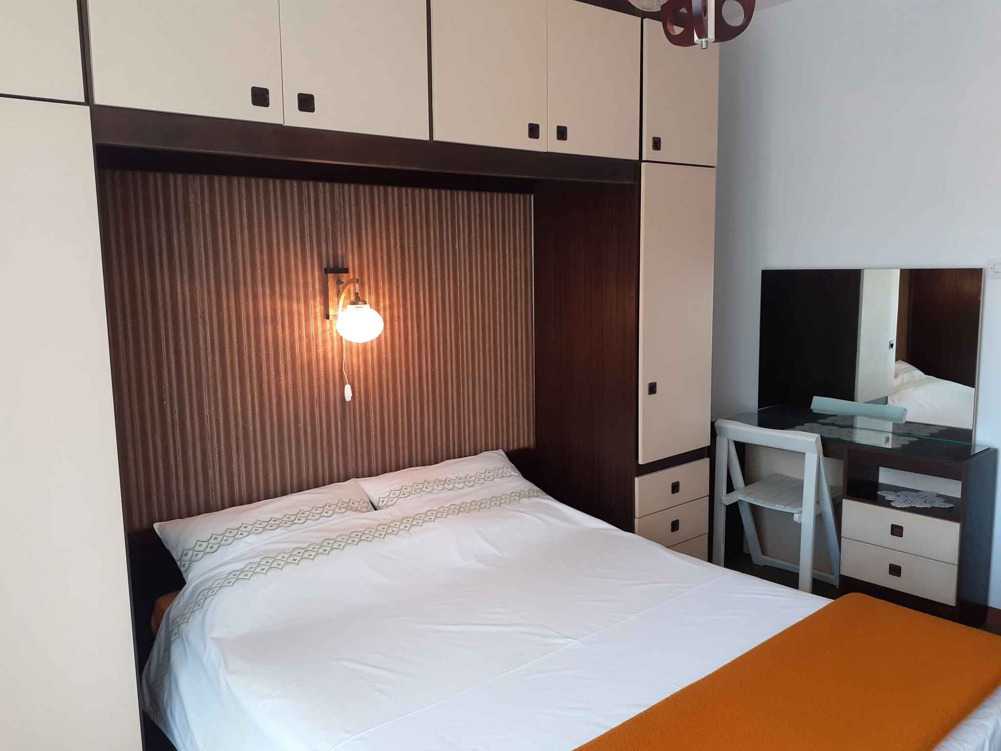 Un dormitorio con cama, escritorio y espejo.