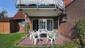 A patio with a table and chairs, a brick wall, and a wooden fence. - Apartment Achterloog (Werdum)