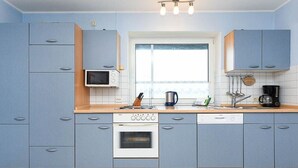 A modern kitchen with blue cabinets, a microwave, a stove, and a dishwasher. - Apartment Achterloog (Werdum)