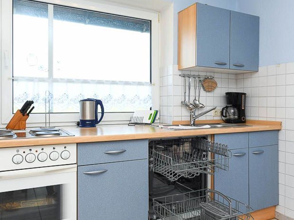 A kitchen with a stove, coffee maker, and dish rack.