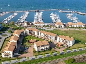 A coastal hotel with multiple buildings, a marina with boats, and a railway track nearby. - (259) 3-room apartment-Hafenstrasse-lake view - apartment complex vacation dreams (Kühlungsborn)
