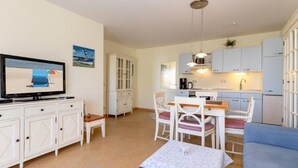 A compact living space with a dining area, kitchenette, and a television in the living room. - (259) 3-room apartment-Hafenstrasse-lake view - apartment complex vacation dreams (Kühlungsborn)
