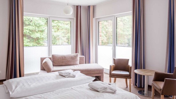 Een hotelkamer met twee bedden, een bank, een tafeltje en een stoel.
