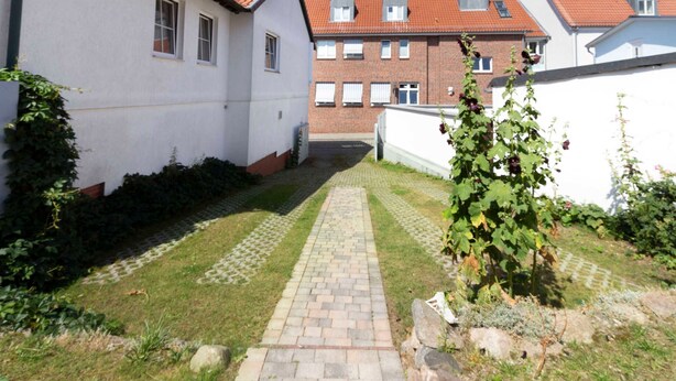 A pathway leading to a building with a brick facade and a white exterior. - Apartment Monima - Apartment (Bergen auf Rügen)