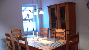 A dining area with a wooden table, chairs, and a cabinet. - Apartment Monima - Apartment (Bergen auf Rügen)